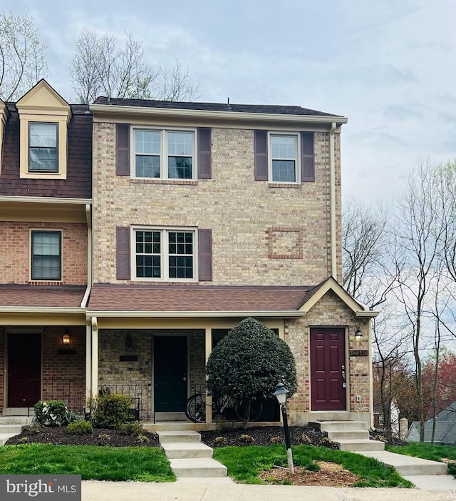 multi unit property with a porch and brick siding