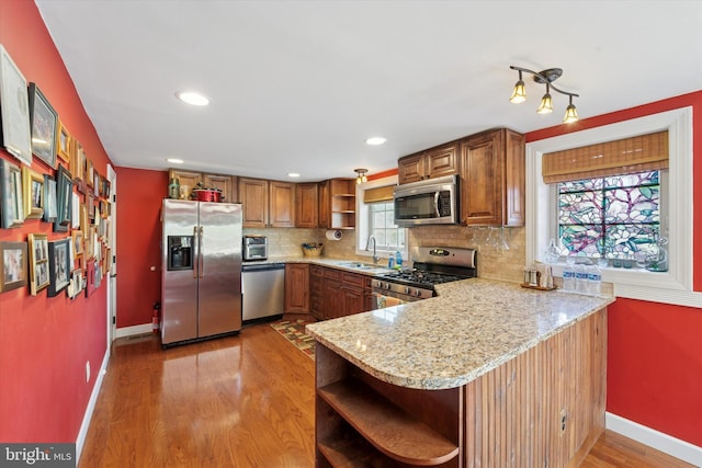 kitchen with open shelves, baseboards, tasteful backsplash, a sink, and appliances with stainless steel finishes