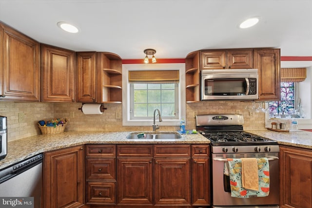 kitchen featuring open shelves, appliances with stainless steel finishes, light stone countertops, a sink, and decorative backsplash