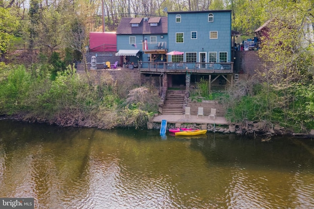 back of house with a deck with water view and stairs