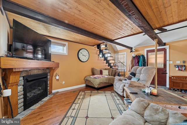 living room featuring wood finished floors, a fireplace, beamed ceiling, baseboards, and wooden ceiling