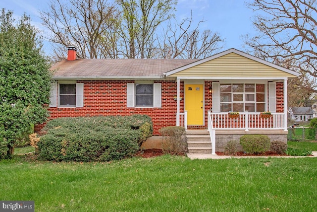 ranch-style home featuring a front yard, a shingled roof, a porch, a chimney, and brick siding