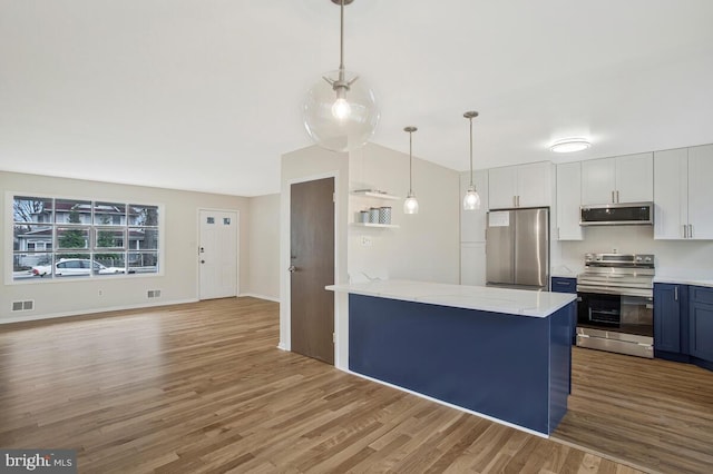 kitchen with a peninsula, blue cabinetry, visible vents, appliances with stainless steel finishes, and wood finished floors