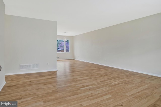 unfurnished room with light wood-style floors, visible vents, and baseboards