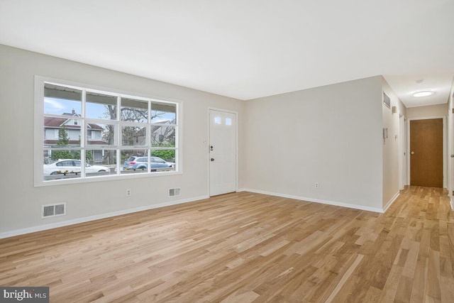 unfurnished living room with light wood-style floors, visible vents, and baseboards