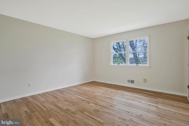 empty room featuring light wood-type flooring, baseboards, and visible vents