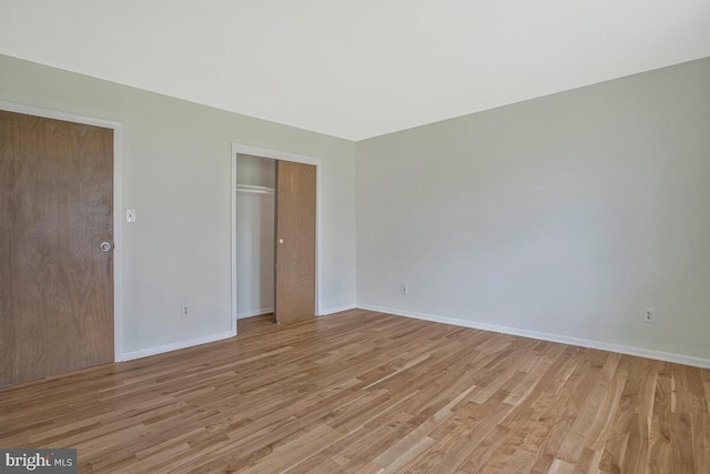 unfurnished bedroom with a closet, baseboards, and light wood-style floors
