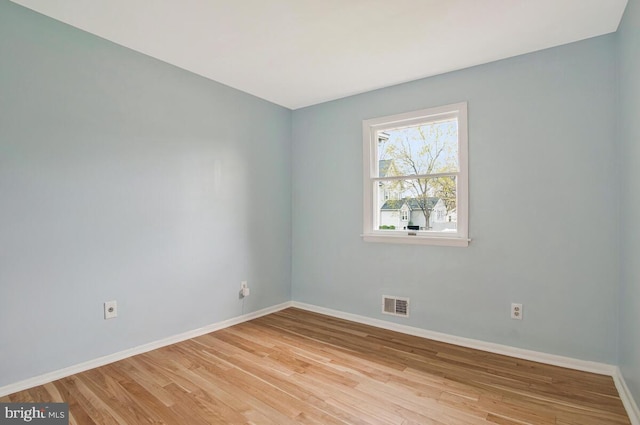 empty room with visible vents, baseboards, and wood finished floors