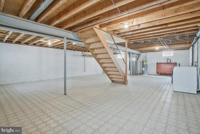 below grade area featuring electric water heater, washer / clothes dryer, heating fuel, and stairs