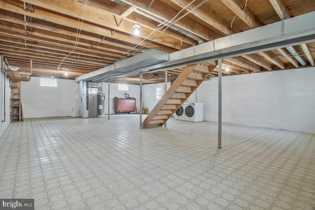 basement with heating fuel, washing machine and clothes dryer, stairs, water heater, and tile patterned floors
