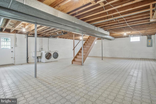 basement featuring independent washer and dryer, electric panel, a sink, stairs, and tile patterned floors