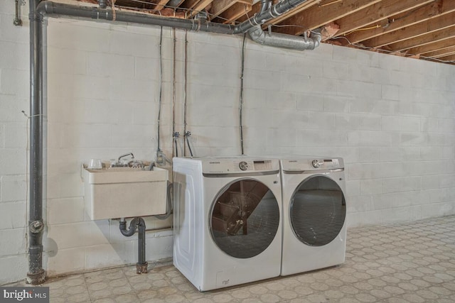 laundry room with tile patterned floors, washing machine and dryer, laundry area, and a sink