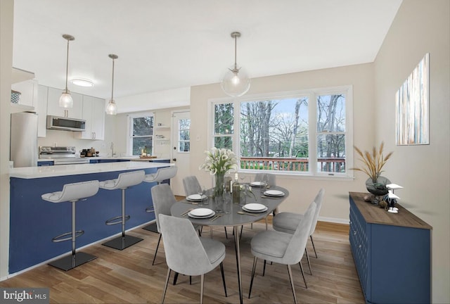 dining space with baseboards and light wood-style floors