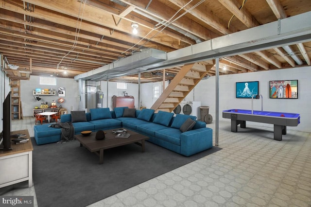 living room featuring electric water heater, stairway, washing machine and dryer, and carpet flooring