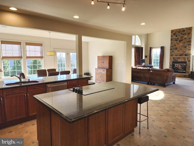 kitchen featuring stainless steel dishwasher, a sink, a breakfast bar, black electric stovetop, and recessed lighting