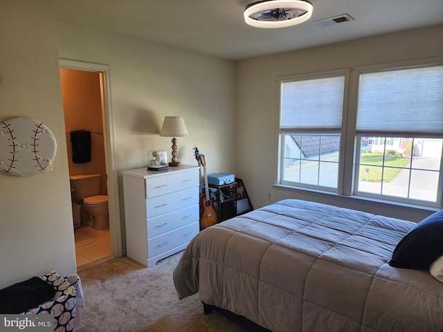 carpeted bedroom with connected bathroom and visible vents