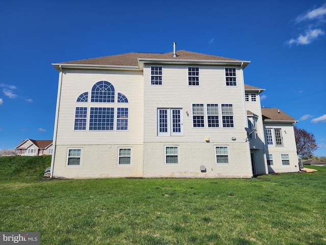 rear view of property with a lawn and brick siding