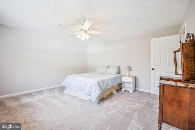 bedroom featuring light colored carpet, ceiling fan, baseboards, and a textured ceiling