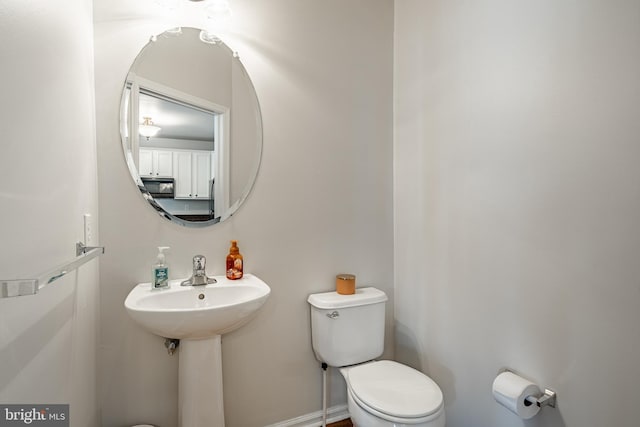 half bathroom with baseboards and toilet