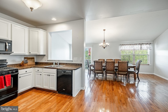 kitchen featuring a sink, black appliances, dark countertops, and a healthy amount of sunlight
