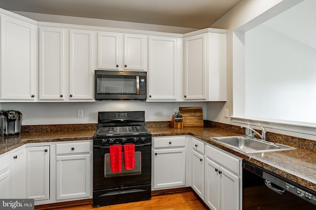 kitchen featuring a sink, white cabinets, and black appliances