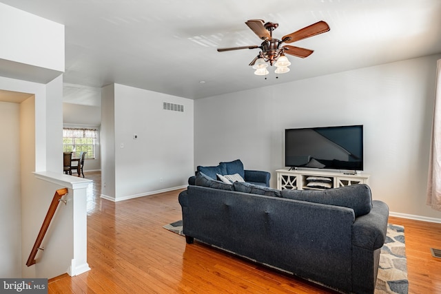 living room featuring baseboards, ceiling fan, light wood-type flooring, and visible vents