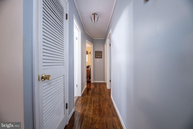 hall featuring dark wood-style flooring, baseboards, and crown molding