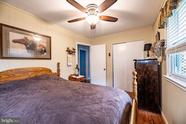bedroom featuring a closet, a ceiling fan, crown molding, and wood finished floors