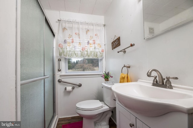 full bathroom with toilet, wood finished floors, vanity, and a shower with shower door
