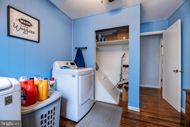 clothes washing area featuring dark wood-type flooring, laundry area, and washer and clothes dryer