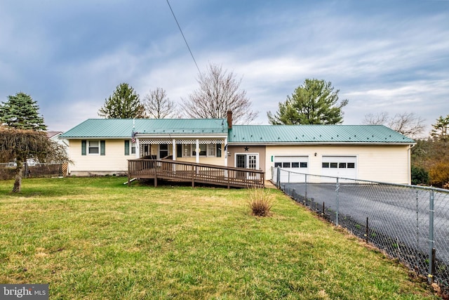 rear view of property featuring a garage, metal roof, driveway, and fence