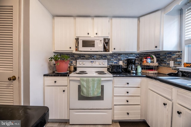 kitchen with tasteful backsplash, white appliances, a sink, and dark countertops