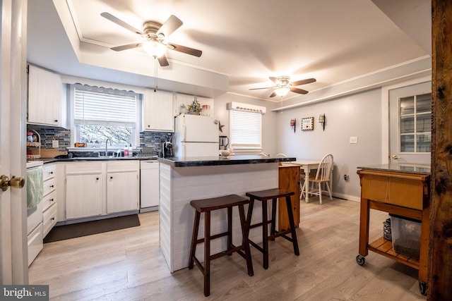 kitchen with a sink, light wood-style flooring, a ceiling fan, and white appliances
