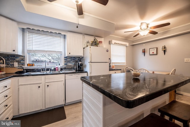 kitchen with white appliances, dark countertops, a kitchen bar, decorative backsplash, and ceiling fan