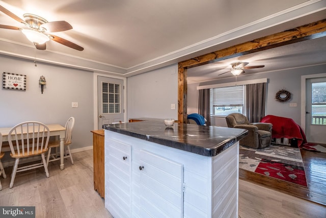 kitchen with light wood-style floors, ceiling fan, dark countertops, and white cabinetry