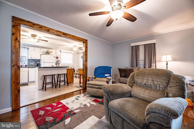 living room with ornamental molding, a ceiling fan, and wood finished floors