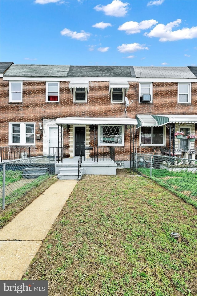 1629 Malvern St, Baltimore, MD 21224 - townhome / multi-family property with a front lawn, a fenced front yard, and brick siding