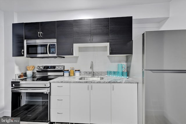 1629 Malvern St, Baltimore, MD 21224 - kitchen with light stone countertops, a sink, stainless steel appliances, and dark cabinetry