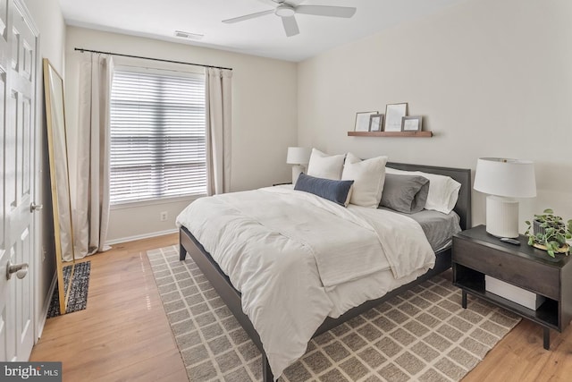 bedroom with light wood-type flooring, ceiling fan, and baseboards
