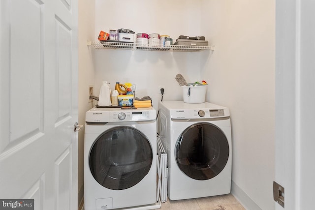 clothes washing area with washing machine and clothes dryer and baseboards