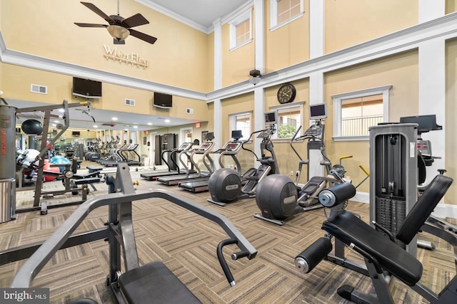workout area featuring ceiling fan, carpet, ornamental molding, a towering ceiling, and baseboards