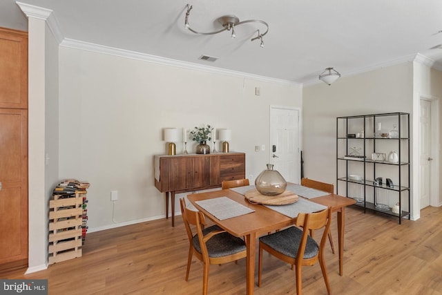 dining room featuring crown molding, light wood-style floors, and baseboards