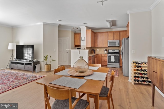 dining area featuring light wood-style floors and crown molding