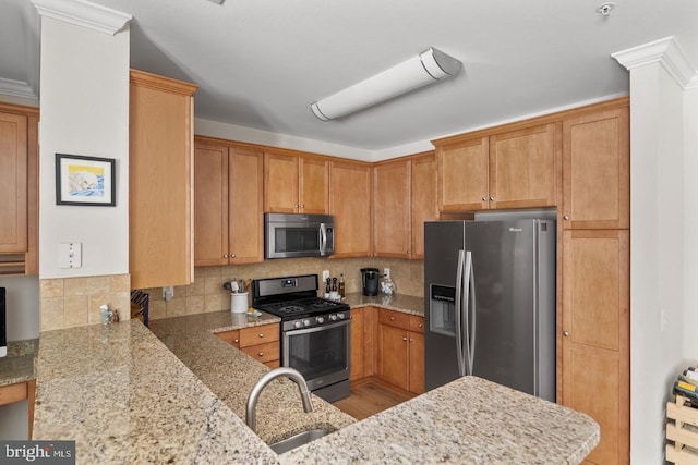 kitchen with stainless steel appliances, a sink, light stone countertops, and decorative backsplash