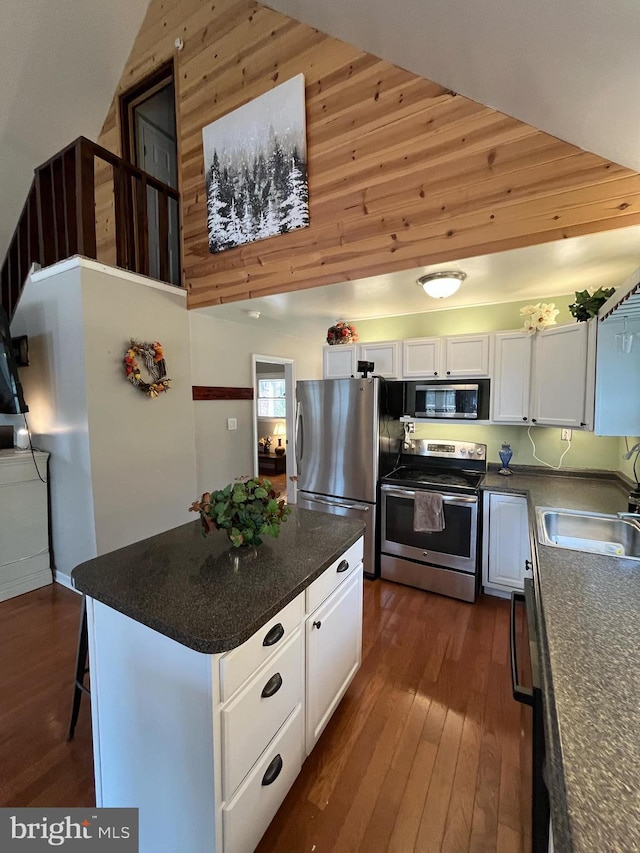 kitchen with white cabinets, a sink, dark countertops, and appliances with stainless steel finishes
