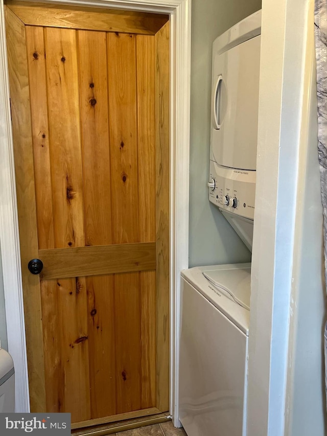 clothes washing area with stacked washer and clothes dryer and laundry area