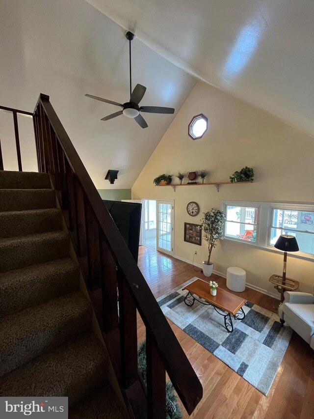 living room with plenty of natural light, high vaulted ceiling, ceiling fan, and wood finished floors
