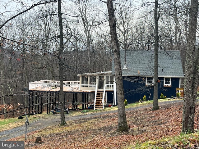 view of front of property featuring roof with shingles, a sunroom, stairs, and a wooden deck