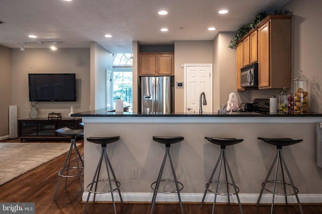 1524 Lincoln Way Unit 409, Mclean, VA 22102 - kitchen featuring stainless steel refrigerator with ice dispenser, black microwave, a peninsula, a breakfast bar area, and brown cabinetry