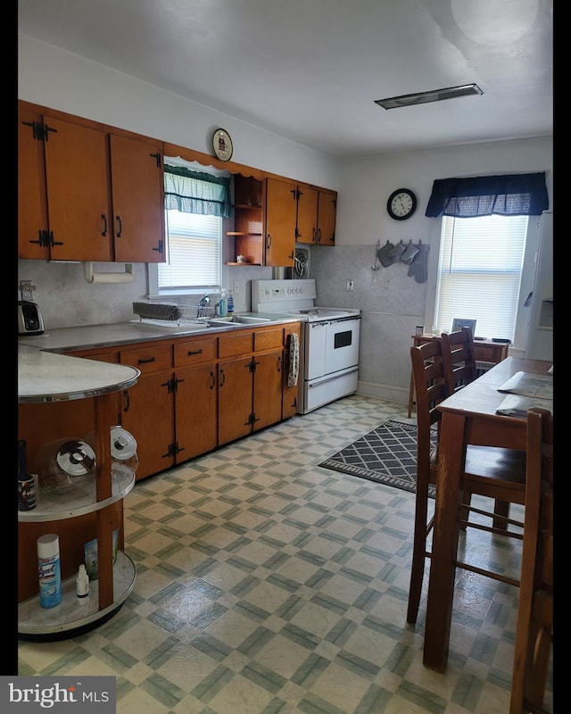 kitchen featuring open shelves, a sink, light countertops, white electric range, and light floors